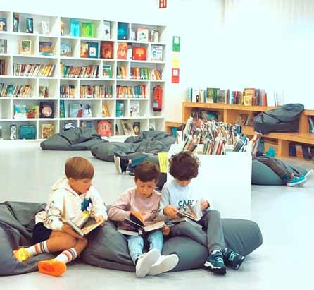 Tres niños sentados en el suelo leyendo libros