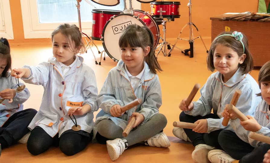Group of girls sitting on the floor behind them a drums